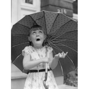 Girl Holding Umbrella Putting Out Hand To Feel For Rain and Looking Up 